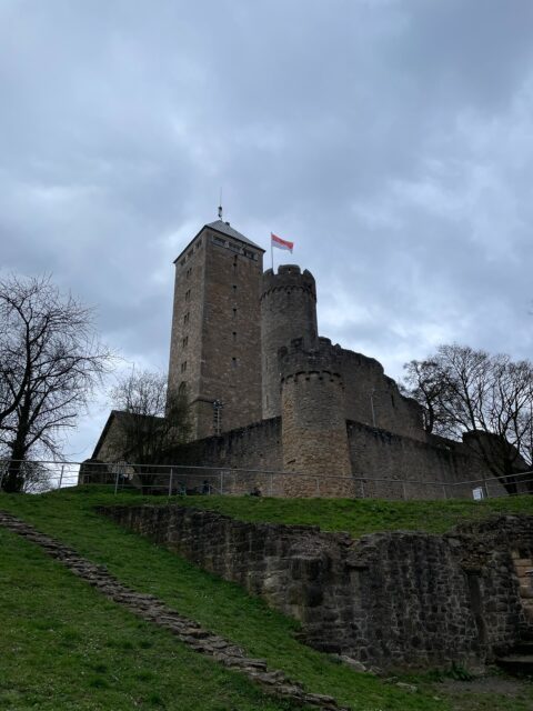Wandertag 2026 🥾⛰️

Am Samstag Morgen den 14 März ging es für die Wös, Jufis und Pfadis in Einhausen los, mit dem Bus Richtung Bensheim. 
Wanderbereit starteten wir vom Bahnhof Bensheim direkt Richtung Weinberge.

Unser Ziel immer im Blick: die Starkenburg in Heppenheim 🏰
Also hieß es: durch die Weinberge, Hügel rauf, Hügel runter und dabei gute Laune statt Höhenmeter zählen ;)

Trotz eher „wechselhaftem“ Wetter haben wir uns nicht unterkriegen lassen – und sind durch den Monsun 🎶 weitergewandert, auch wenn hin und wieder ein Motivationskeks nötig war. 

Oben angekommen haben wir die Burg ausgiebig erkundet und jeden Turm mindestens einmal bestiegen 🏰

Danach machten wir uns wieder auf den Weg nach unten, über den Planetenweg, durch die Heppenheimer Altstadt zum Bahnhof und mit dem Bus wieder heim nach Einhausen

#pfadfinder #wandernmachtglücklich #starkenburg #scouts #giggelontour